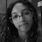 Young person with curly hair and glasses.