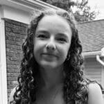 Smiling girl with curly hair in black and white.